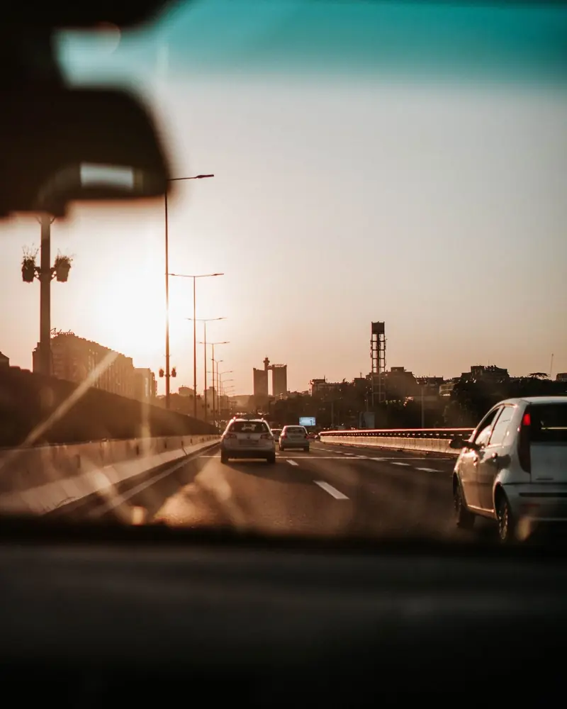 A city highway at sunset seen through a car windshield